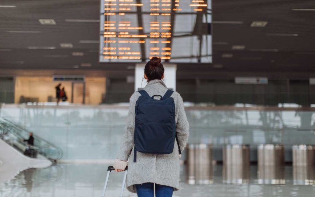 Woman at the airport, checking the flight schedule on the arrival departure board