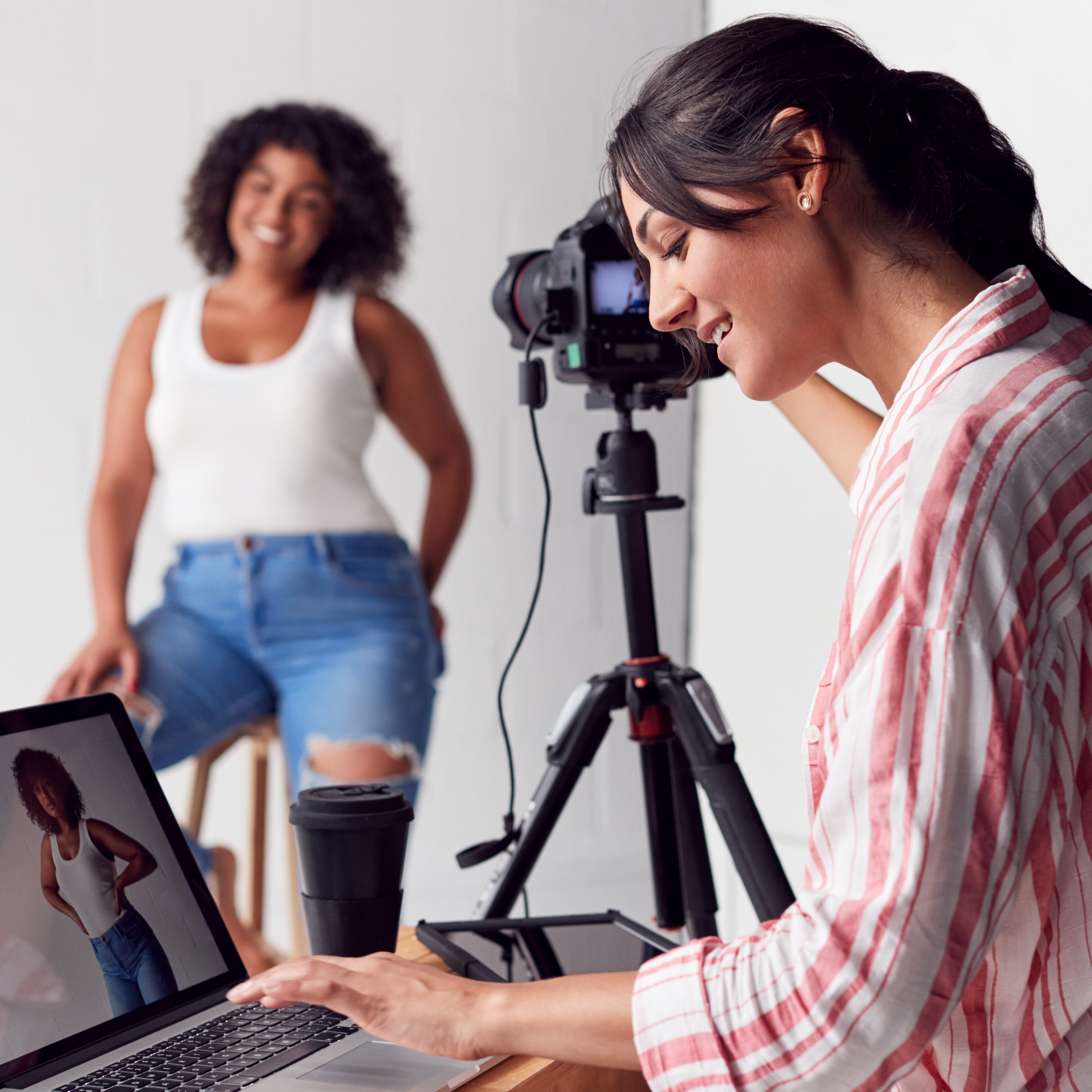 Female Photographer In Digital Studio Shooting Images On Camera Tethered To Laptop Computer