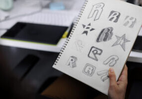 Hand Holding Notebook With Drew Brand Logo Creative Design Ideas